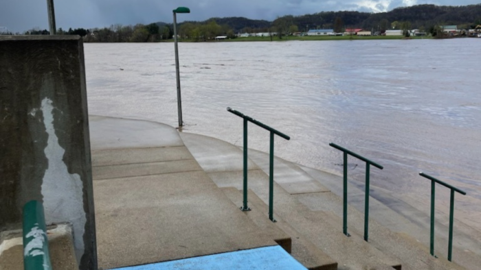 Platform and concrete bleachers along Ohio River bank shows river water covering the concrete steps on an overcast day.