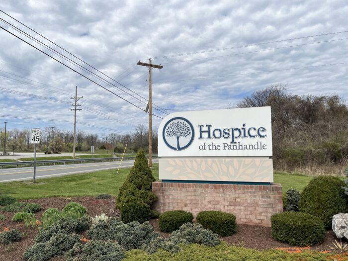 A sign with a tree graphic reads "Hospice of the Panhandle." It sits above a small garden.