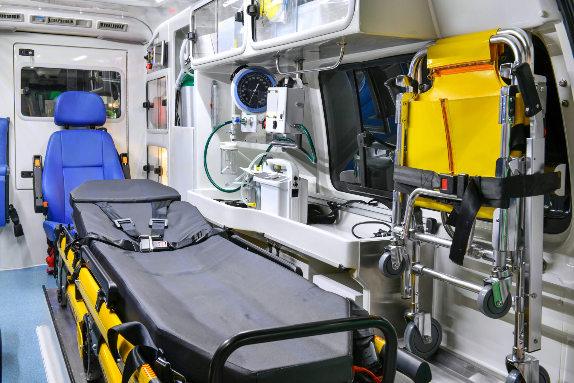 The interior of an ambulance is shown with a stretcher cleaned and a blue chair for a paramedic.