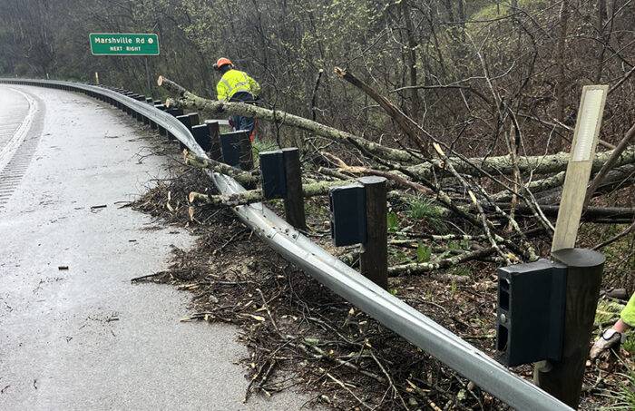 A state worker walks along an interstate moving debris after flooding.