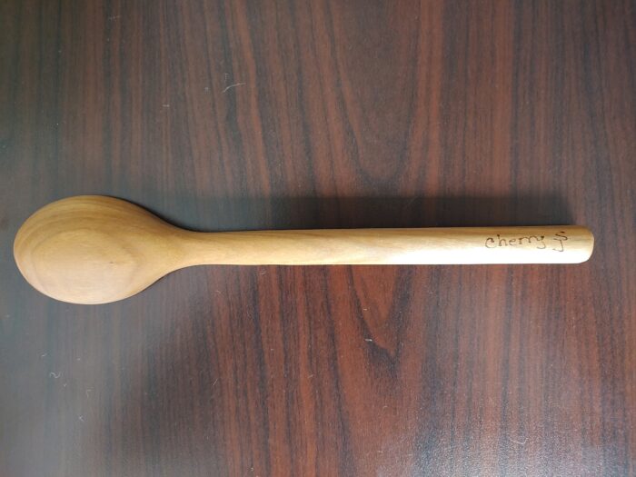 The back of a wooden spoon. On the handle, it reads, "cherry SJ."
