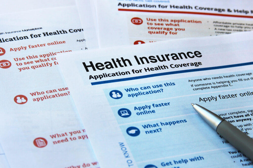 A pen lays on documents to sign up for health insurance.