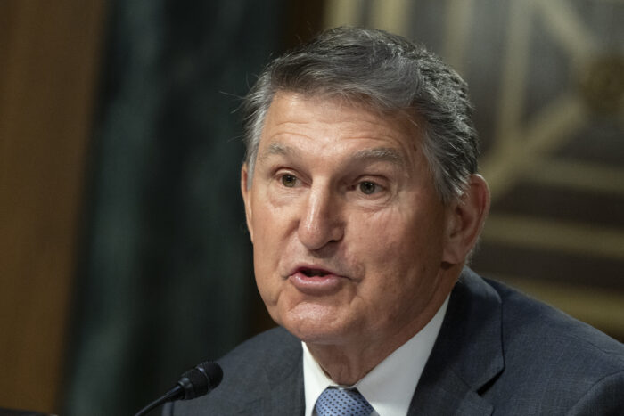 Close up photo of an older man wearing formal attire. He has salt and pepper colored hair and is talking into a podium microphone.