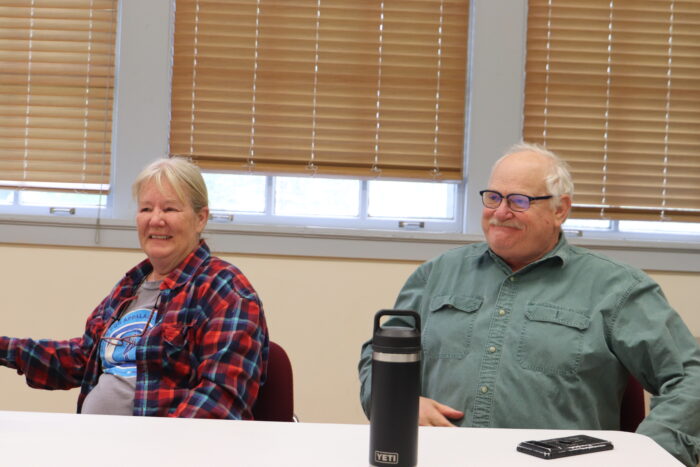 An older man and woman sit at a table in a former school converted into a community center.