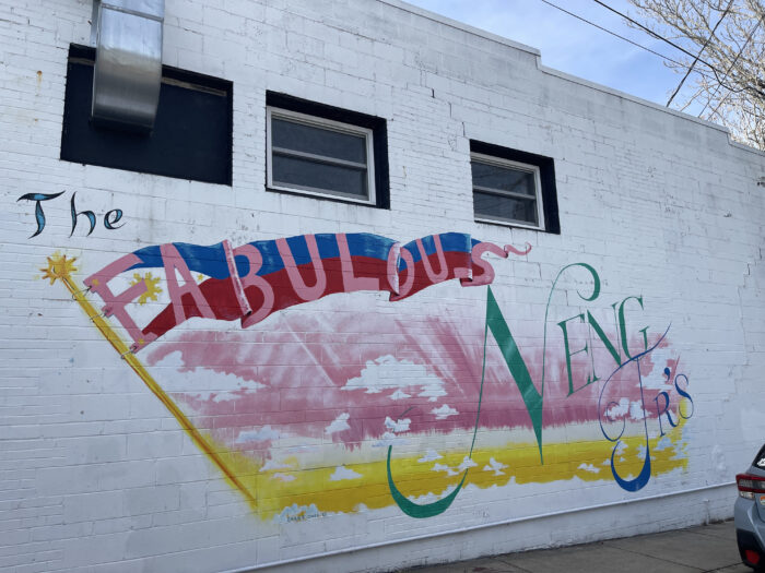 Drawings and paint can be seen on the side of a white building. It says, "The Fabulous Neng Jr.'s."