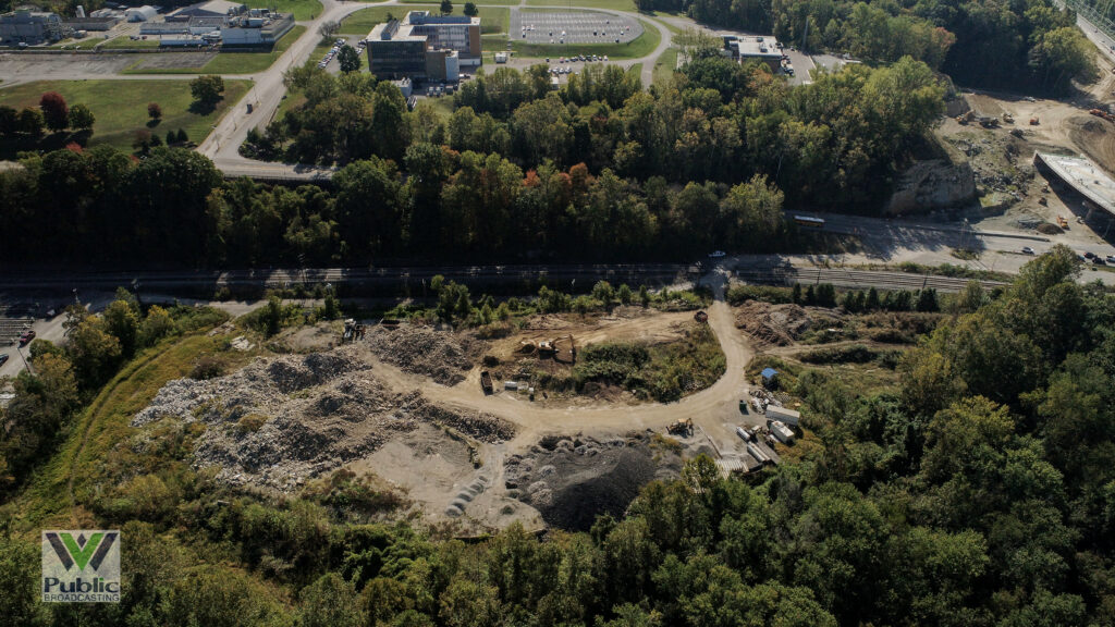 An industrial site is filled with construction debris and surrounded by vegetation, viewed from overhead by a drone.