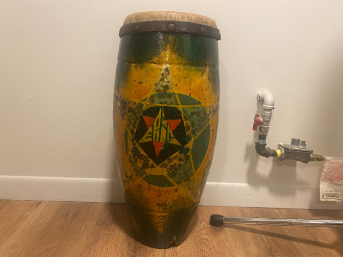 A photo of a drum. The drum is tall and meant for hand use. The drum is green and yellow and features a star in the center.