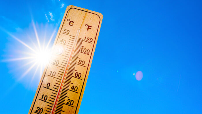 Blue sky with bright sun and thermometer.
