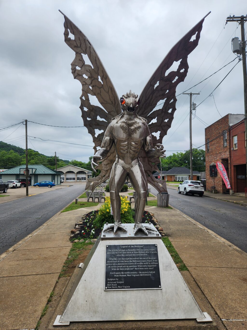 stainless steel statue of a mysterious creature with red eyes and large wings.