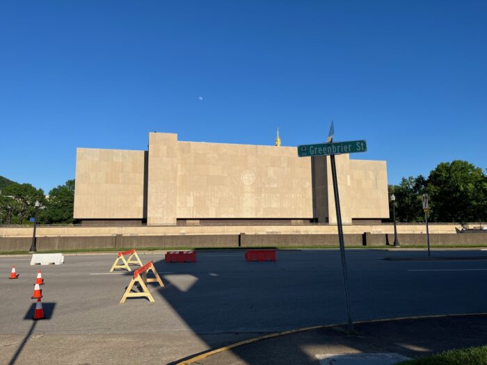 A large masonry building basks in the afternoon sunlight on a clear day with a public street in front.