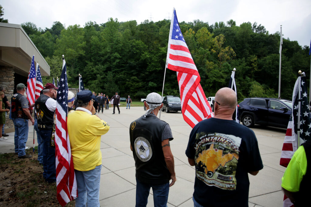 View from behind a number of volunteers paying their respects at a funeral.