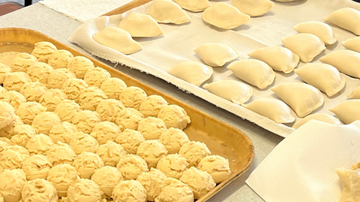 A closeup of two baking sheets of uncooked pierogie dough.