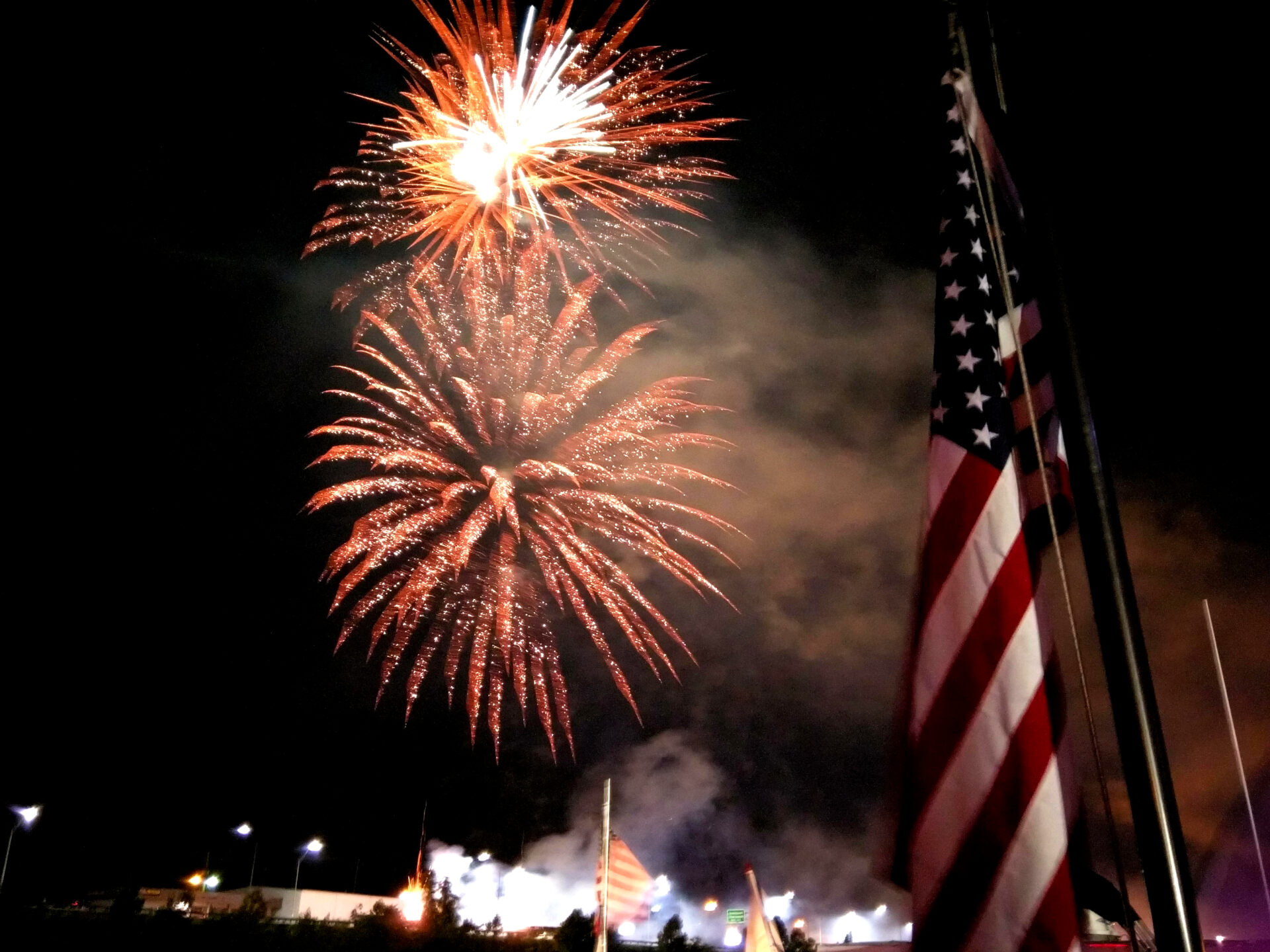 two firework blasts by a flag