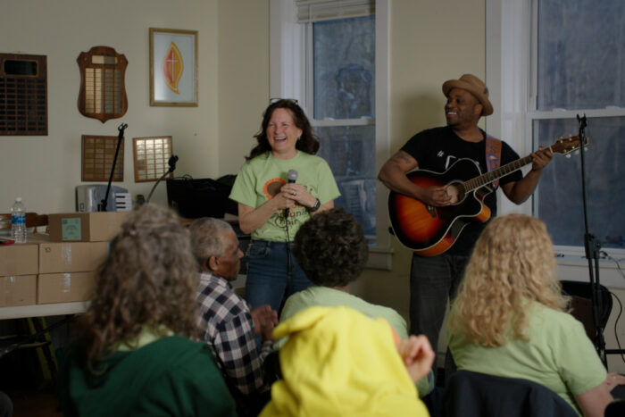 A woman and a man lead a gospel sing in front of a group of people in a church.