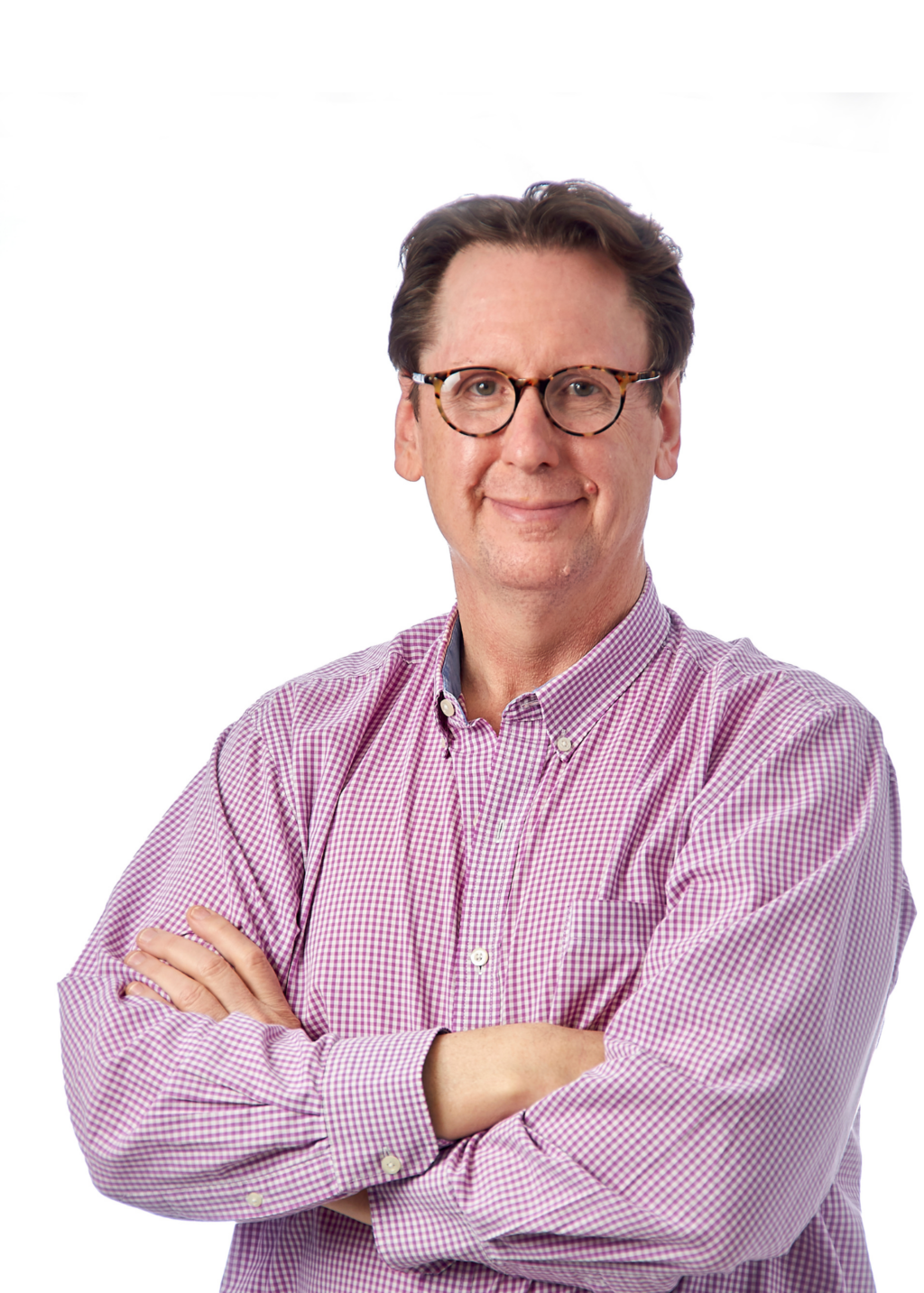 A white man with brown hair and glasses is standing with his arms crossed. He is wearing a pink and white checkered button down.