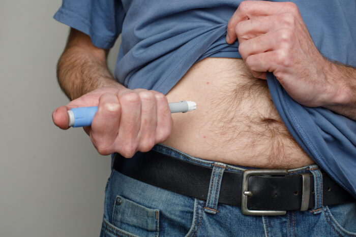 Man wearing blue t-shirt injects his stomach semaglutide or Insulin Injection Diabetes Drug.
