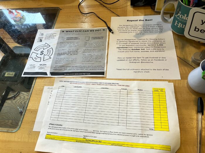 Three pages of text are arrayed on a counter. The page closest to the bottom of frame is dominated by a table of cells with the right two columns highlighted yellow.