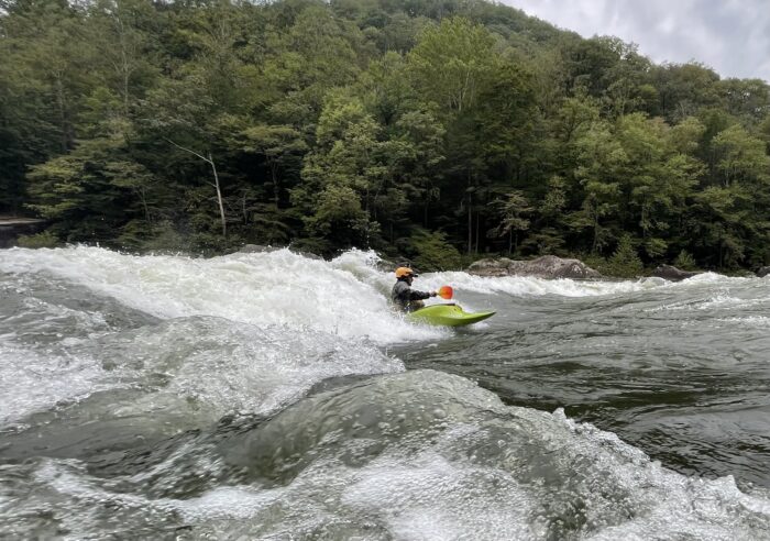 a man on a kayak surfs a large way.