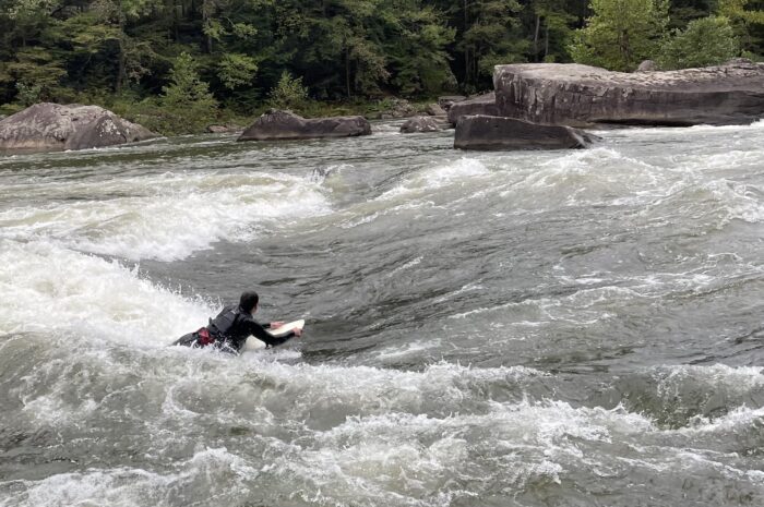a man body surfs in a ocean wave. He looks small compared to the wave.