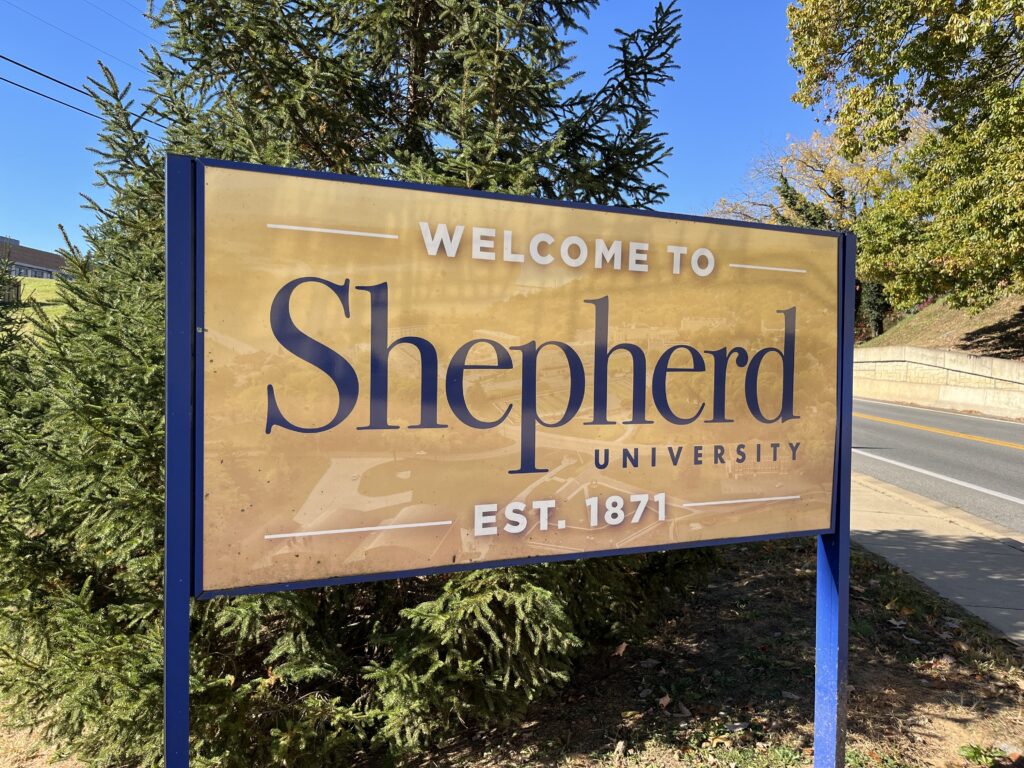 A sign along a road reads "Welcome to Shepherd University, Est. 1871."