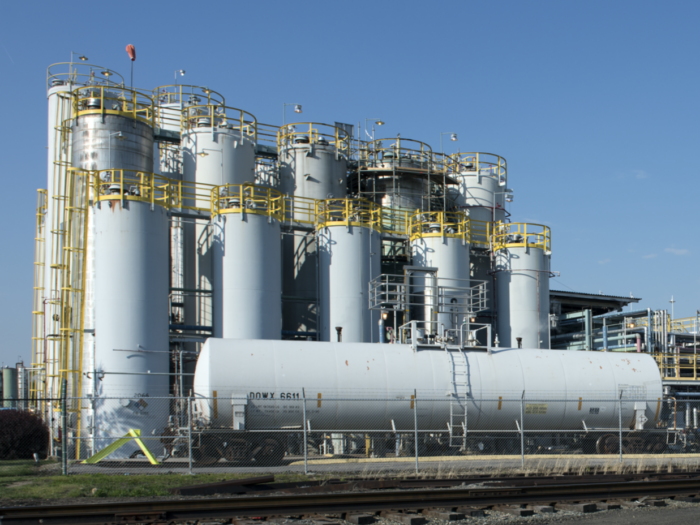 A chemical plant with tall, cylindrical structures and metal fencing atop them.