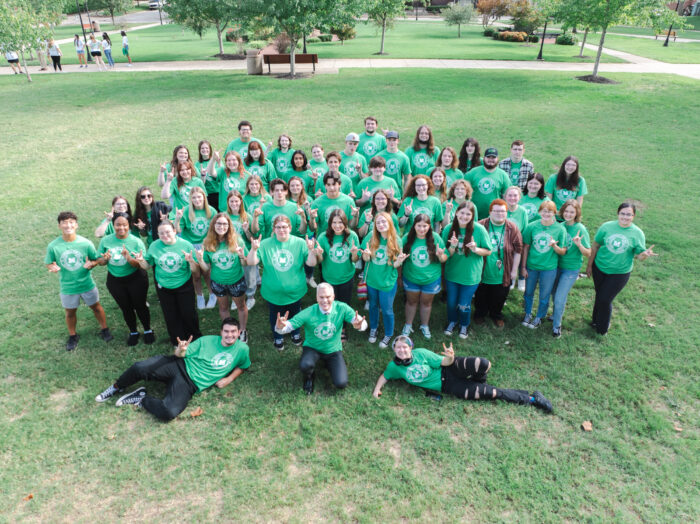 Large group of people, all in green t-shirts, posing for the camera.