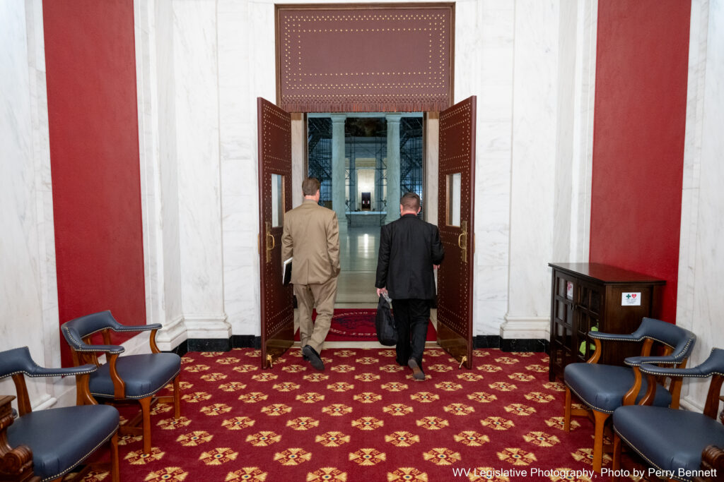 two men walking out of a double door into a dark rotunda