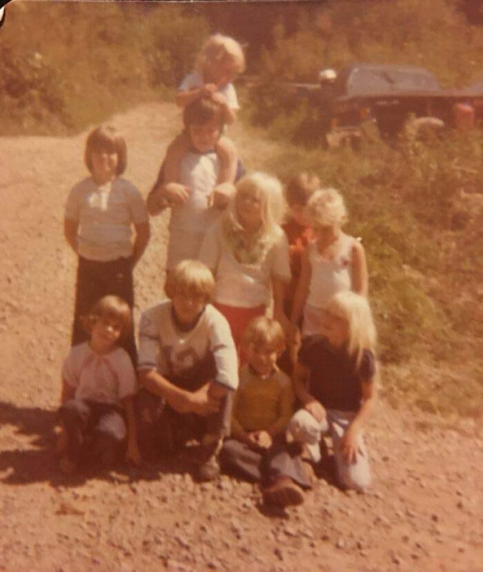 A family photo from the 1970s. Ten children pose together for a photo. They are outside, and it's a sunny day.