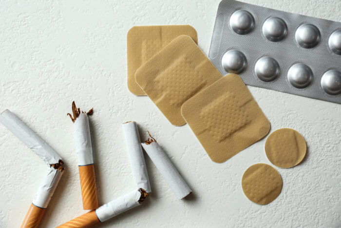Nicotine patches, pills and broken cigarettes on white background, lay flat.
