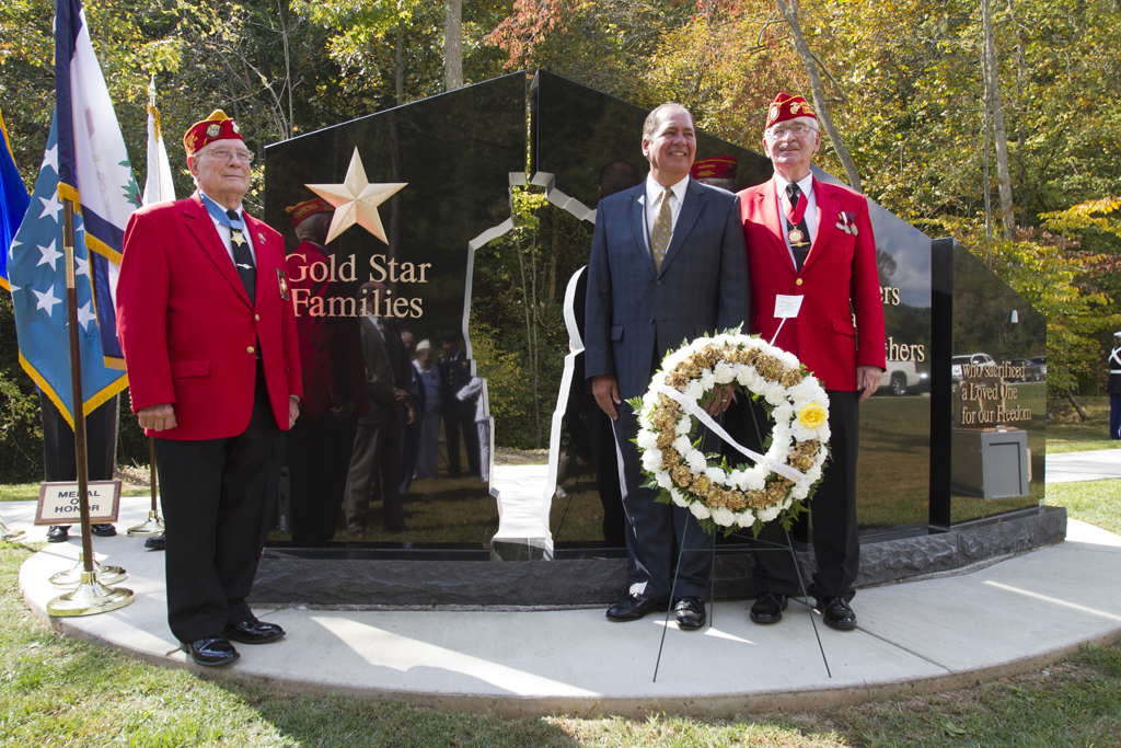 Three men stand in front of a monument