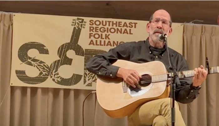 A man plays and sings on a stage for the Southeast Regional Folk Alliance Festival.