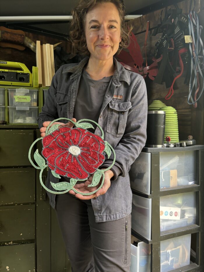 A woman in grey shows off an elaborate flower crafted from recycled climbing rope.