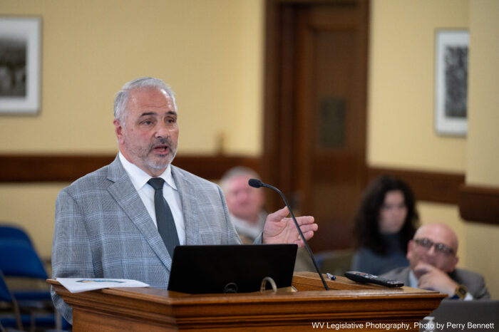 man speaks at a podium with a microphone and laptop