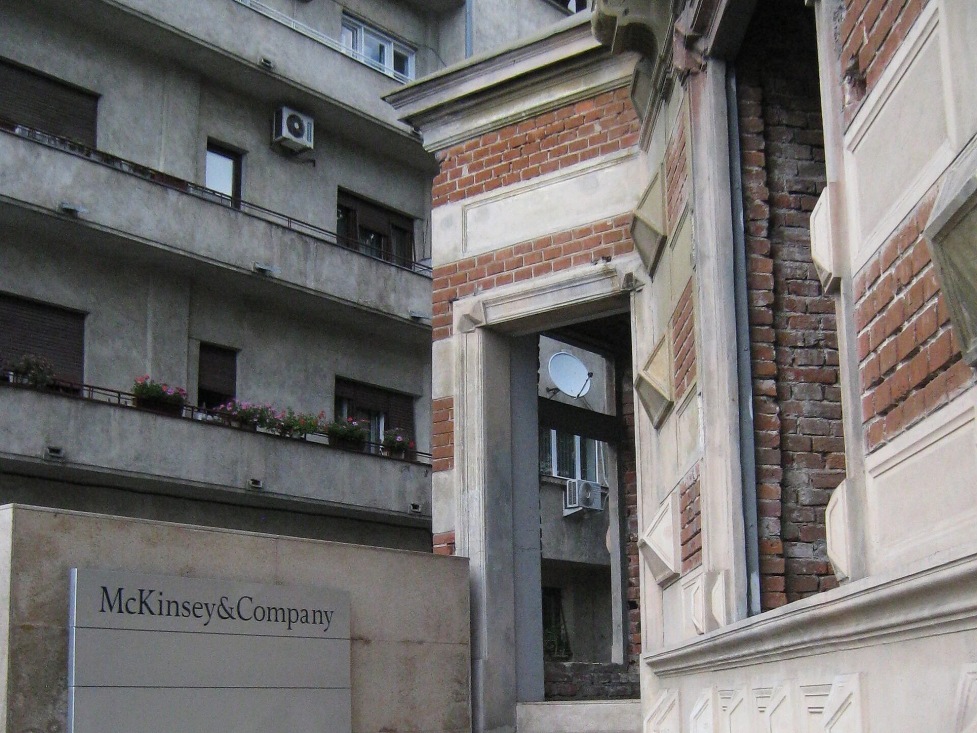 A brick and concrete building has a sign next to its doorway that reads "McKinsey & Company."