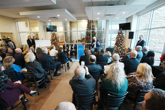 room full of people in chairs facing away from camera watching a speaker