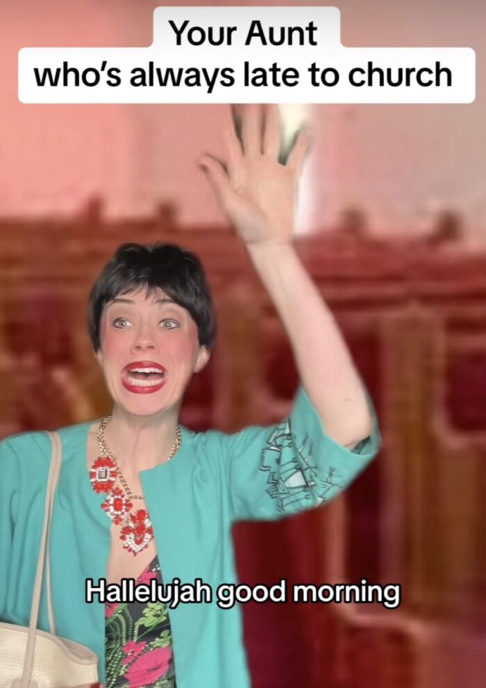 A woman is shown in a vertical video playing a character. She is wearing a black wig and making a funny face. She wears a blue shirt over another colorful one. Her hand is raised in praise. Above her are the words, "Your Aunt who's always late to church." Below her are the words, "Hallelujah good morning."