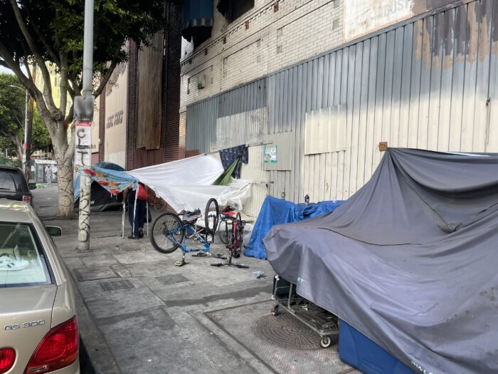 A sidewalk featuring makeshift tents for homeless.