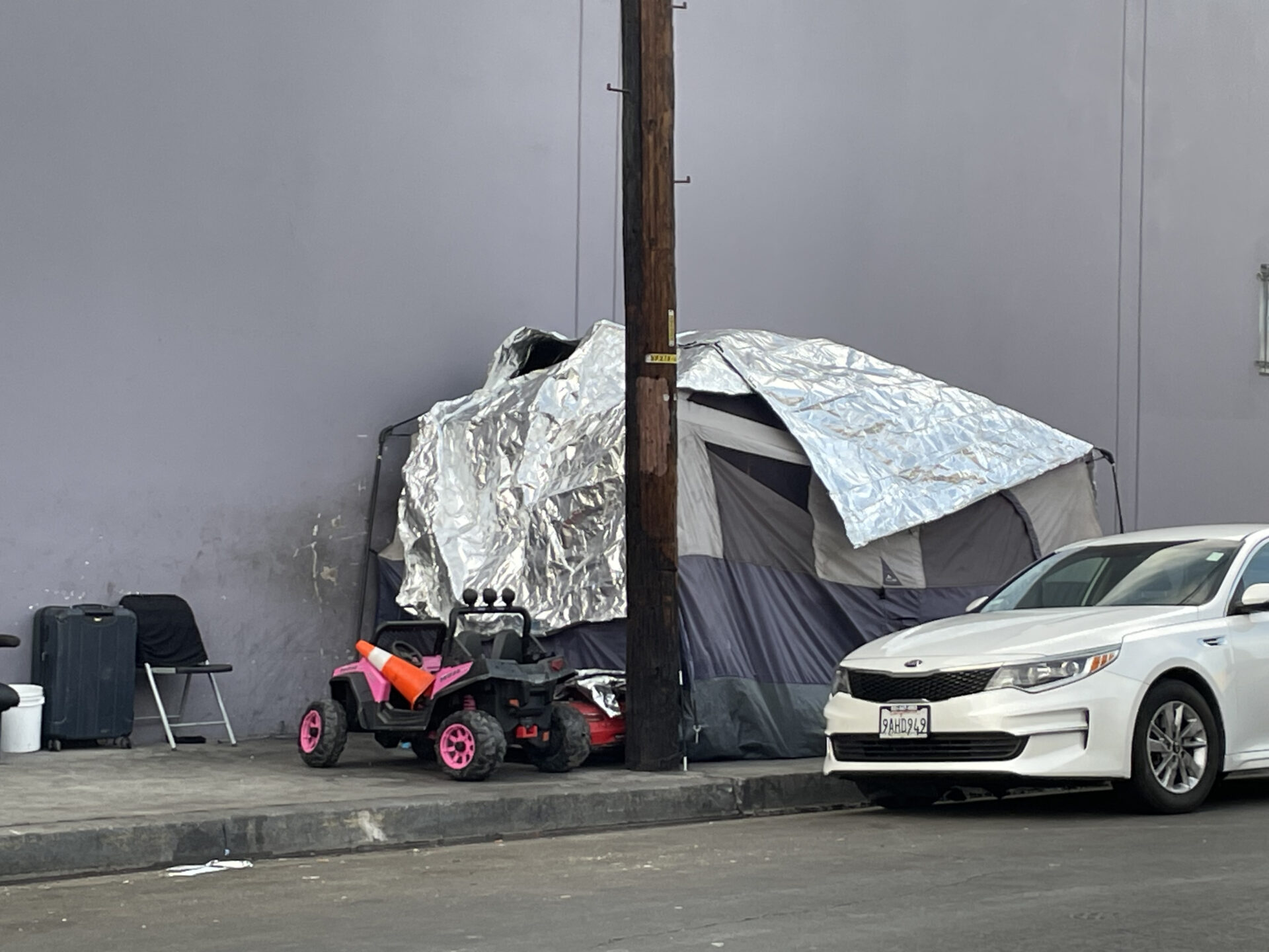 A photo of a makeshift tent for the homeless. Next to it is a child's jeep toy.