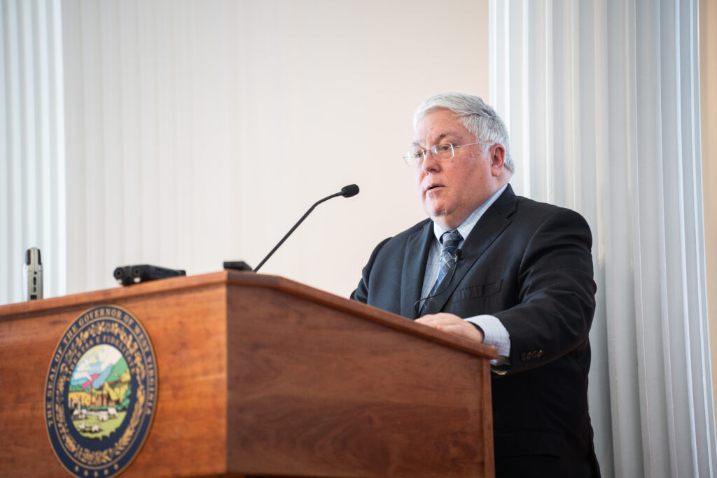 man stands speaking at a podium