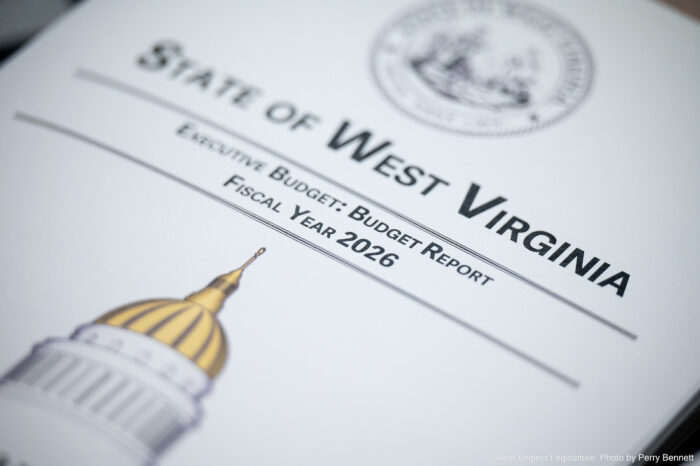 A packet of papers is topped with a page that reads "State of West Virginia Executive Budget: Budget Report Fiscal Year 2026." Above the text is a seal of West Virginia, and below it is a drawing of the golden dome of the West Virginia State Capitol.