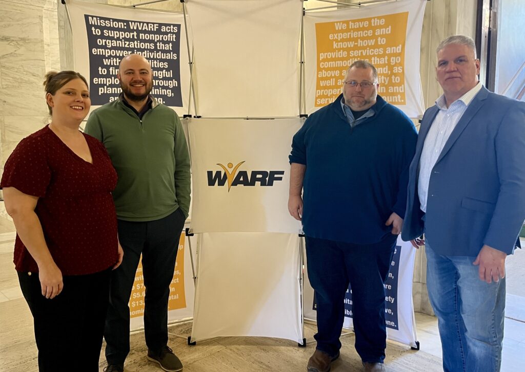 Two people stand on each side of a white sign that reads "WVARF."