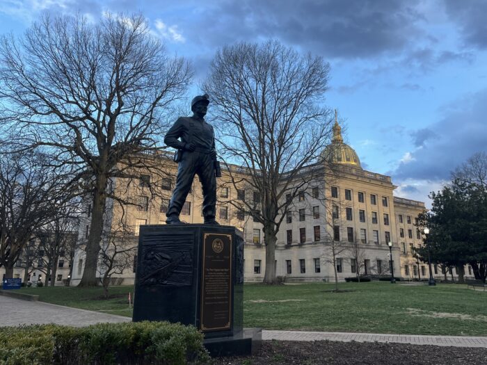 A black statue of a coal miner sits in a garden outside the State Capitol building.