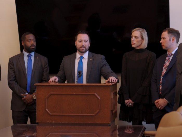 Four people in formal attire stand around a podium.