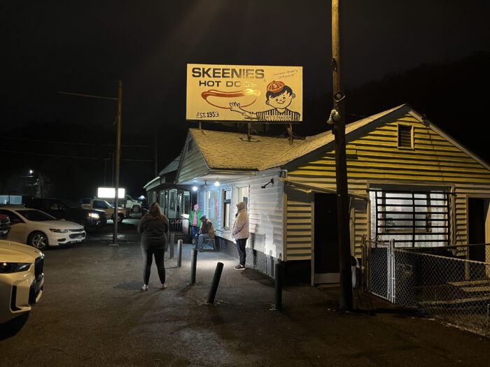 Photo of a building at nighttime that has a sign on top that says "Skeenies".