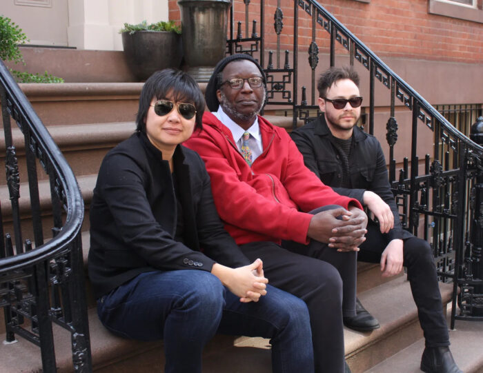 Three people sitting outside on a stoop of stairs.