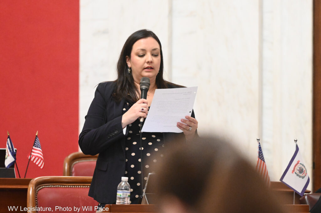 A woman holding a piece of paper stands up and speaks.