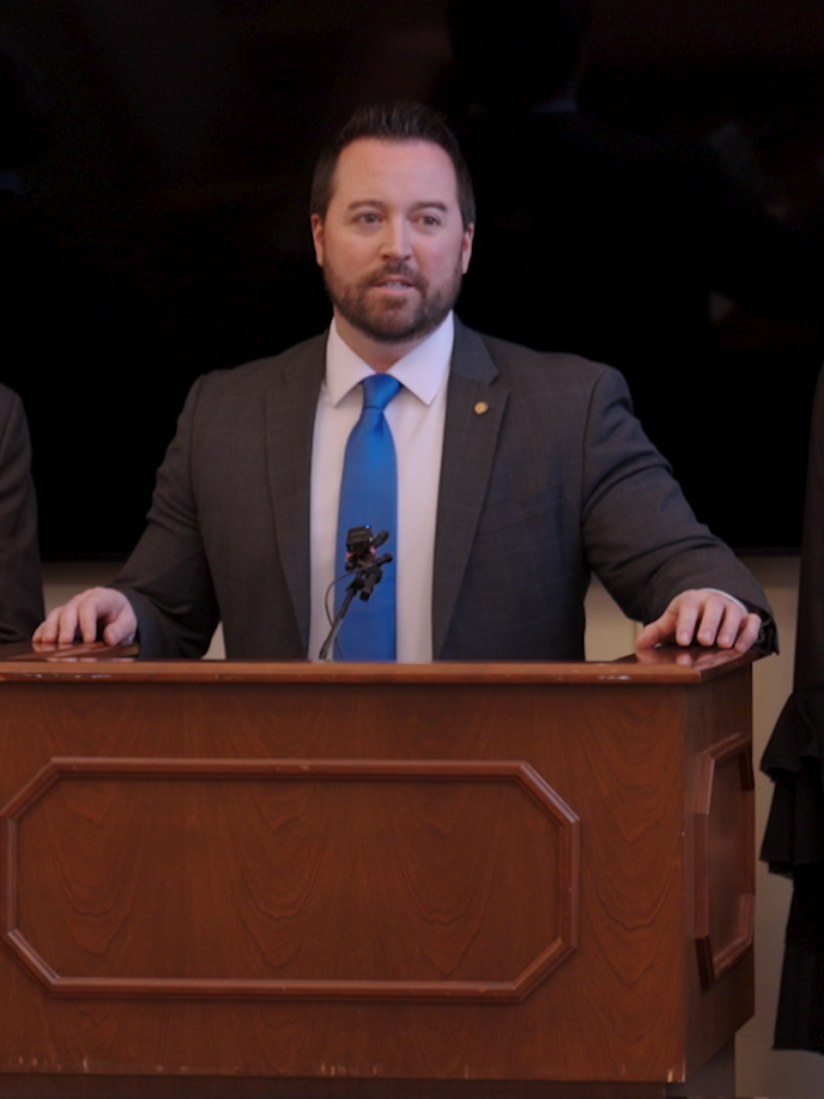 Four people in formal attire stand around a podium.