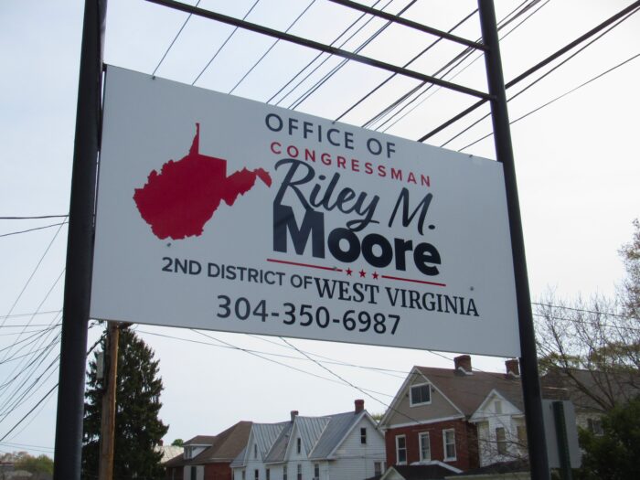 A sign on a town street reads "Office of Congressman Riley M. Moore."