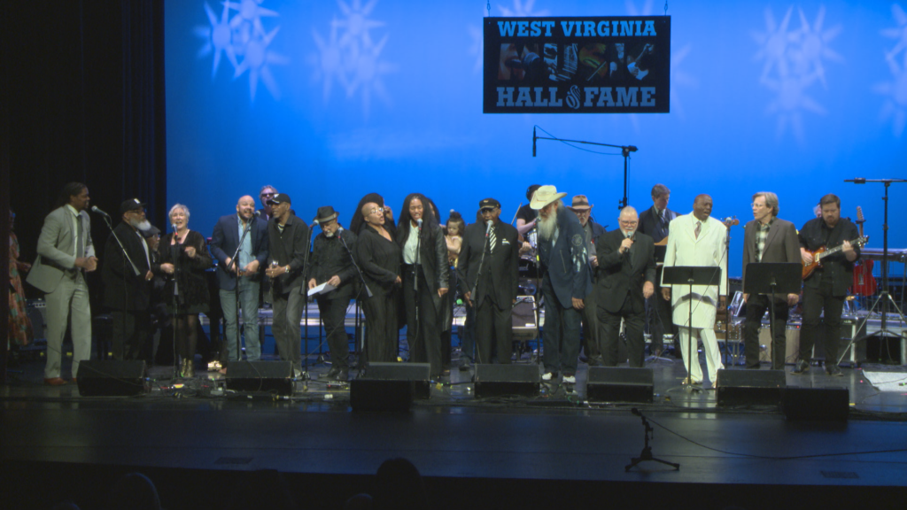 Men and women lined up across a stage performing.
