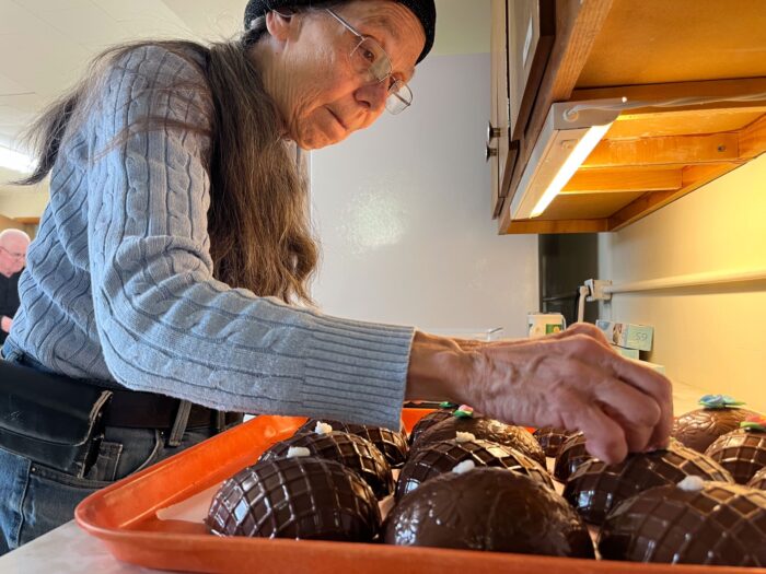A white woman decorating chocolate eggs.